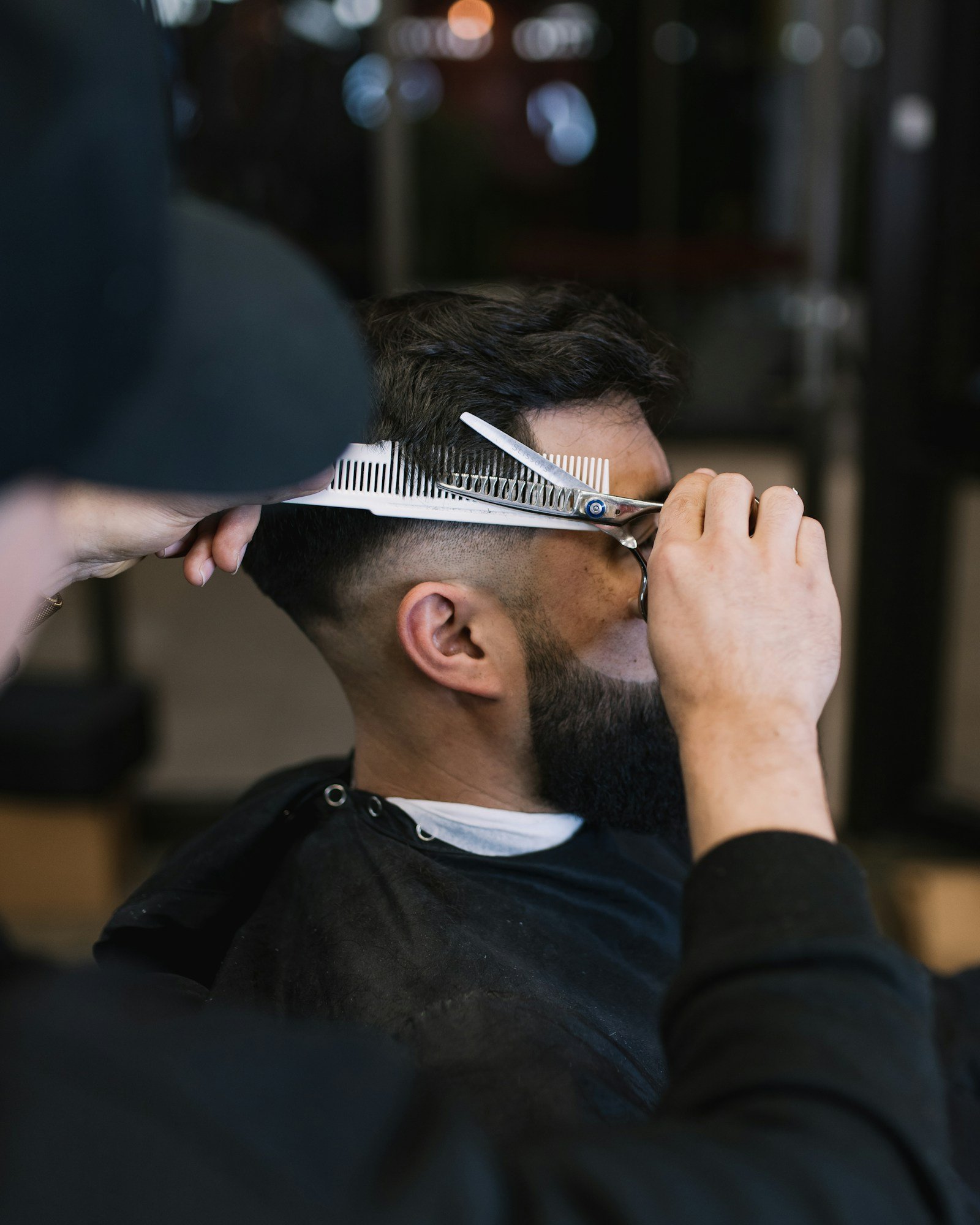 Schere und Kamm auf dunkler Ablage im Barbershop