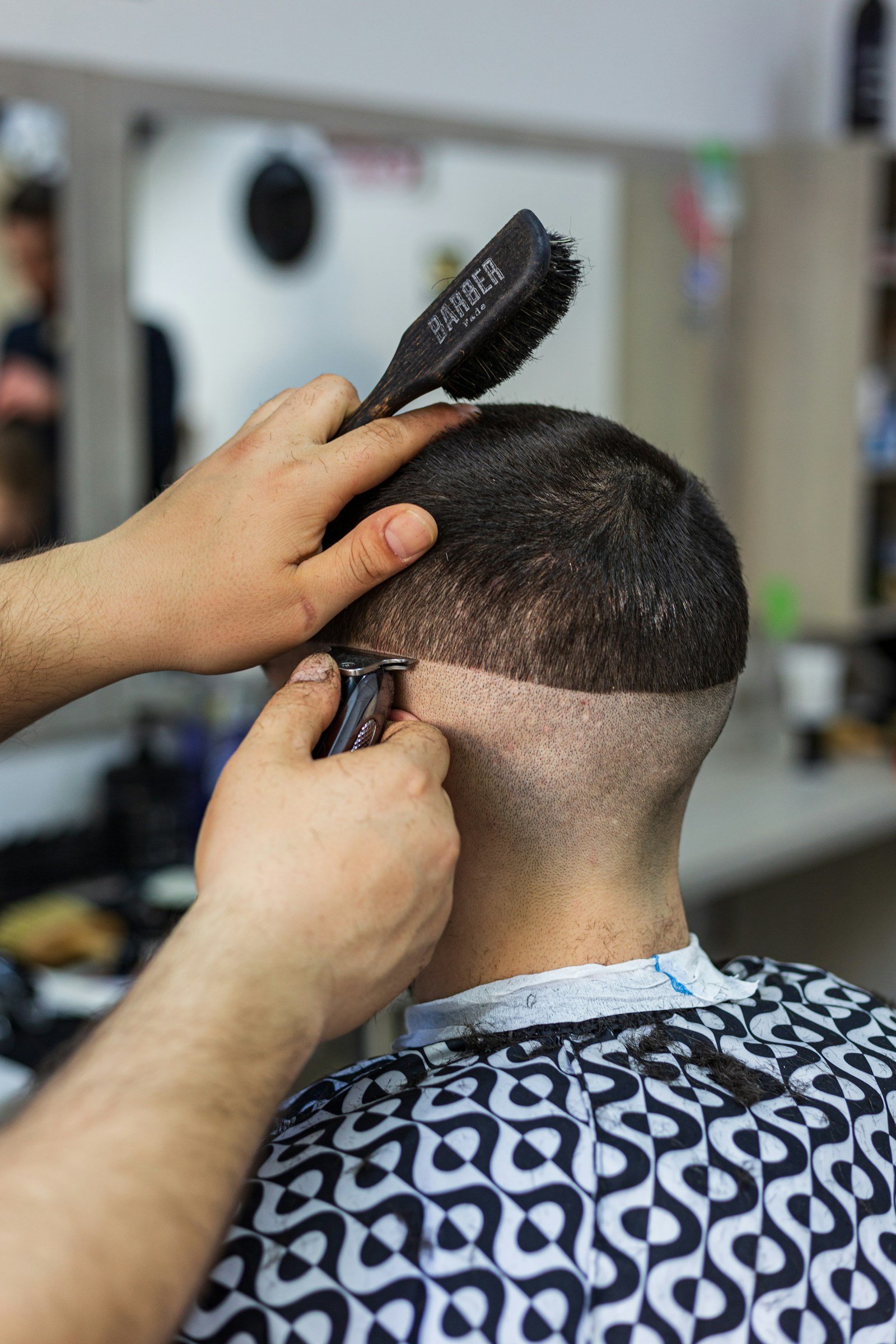 Barbier führt die Haarschneidemaschine für einen Fade an der Schläfe